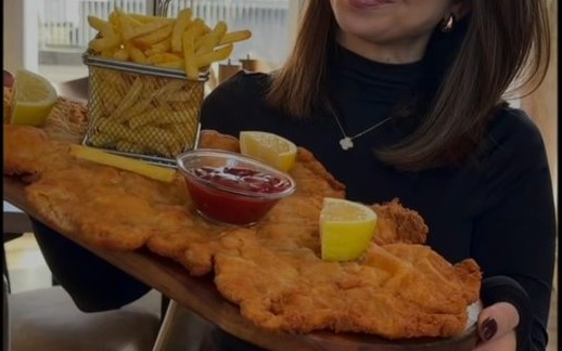 Das XL Schnitzel auf dem Holzbrett, von einer Gastin getragen