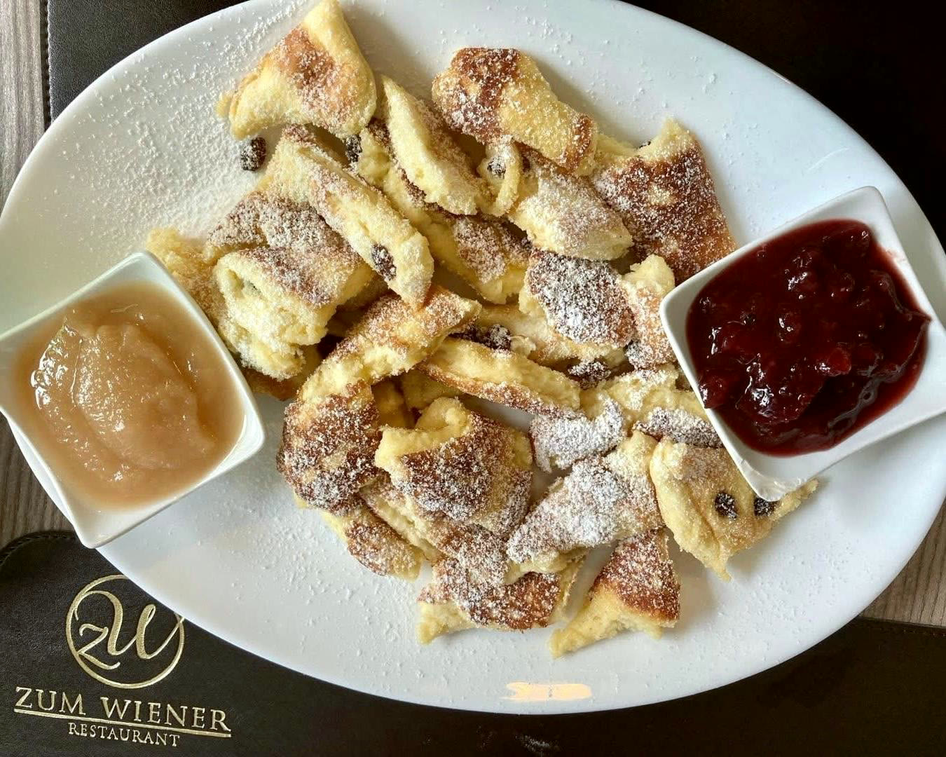Kaiserschmarrn mit Apfelmus und Zwetschgenröster auf dem Tischset mit goldenem Monogramm