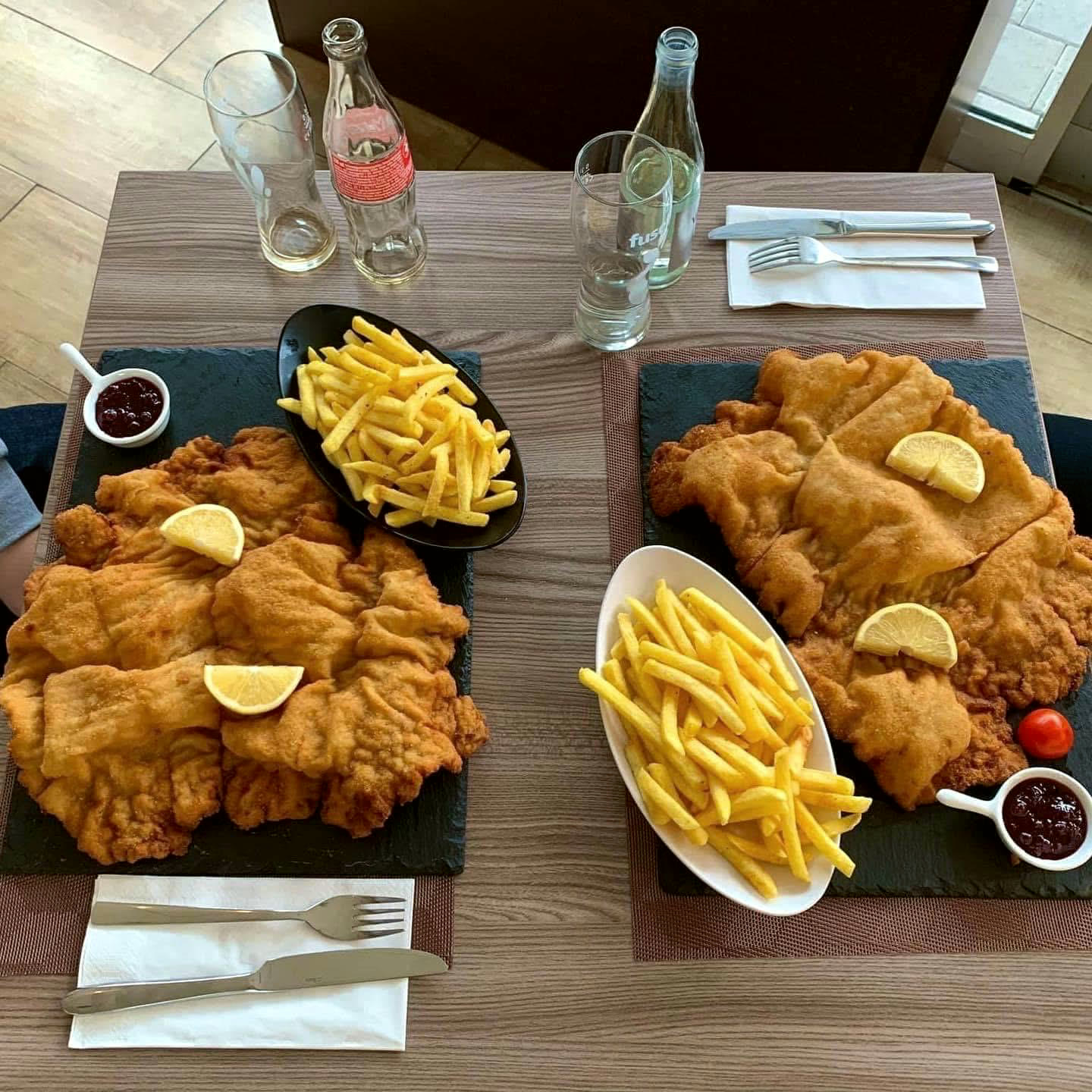 Zwei grosse Wiener Schnitzel mit Pommes frites und Preiselbeeren auf Schieferplatten